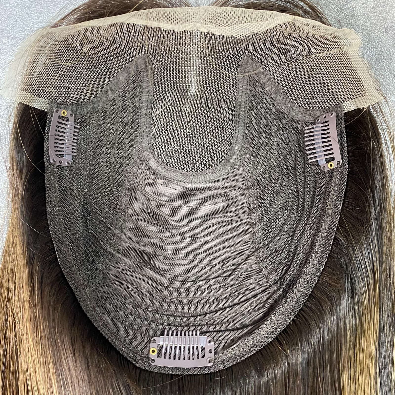 Close-up of a brown lace topper cap with a transparent lace front and pressure clips