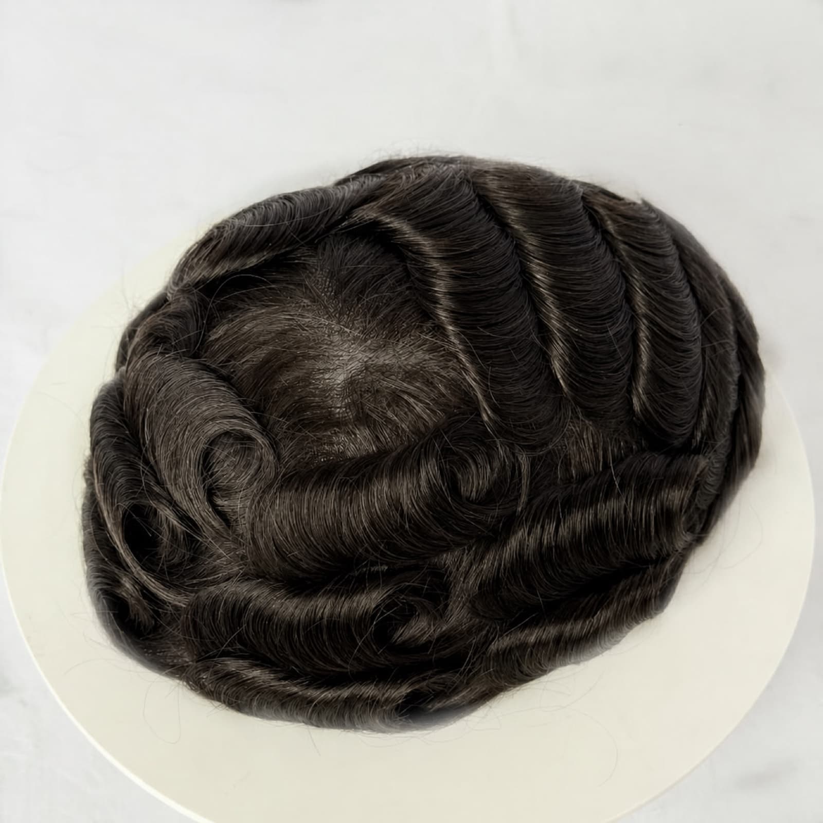 Top view of a black wavy men's hair system showing its styled texture