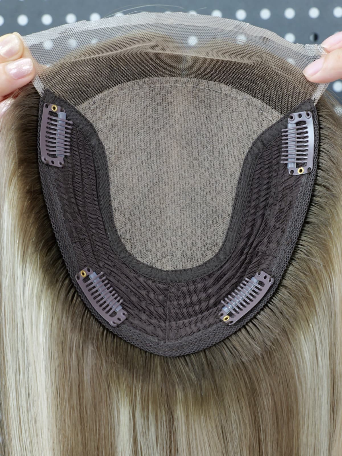 Close-up of a blonde silk topper with a transparent lace front and pressure clips