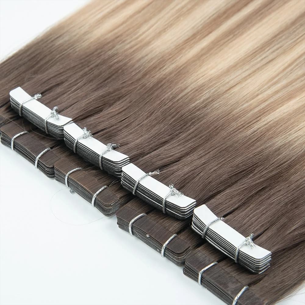 Brown-to-blonde tape-in hair extensions arranged in rows with stacked attachment tabs visible