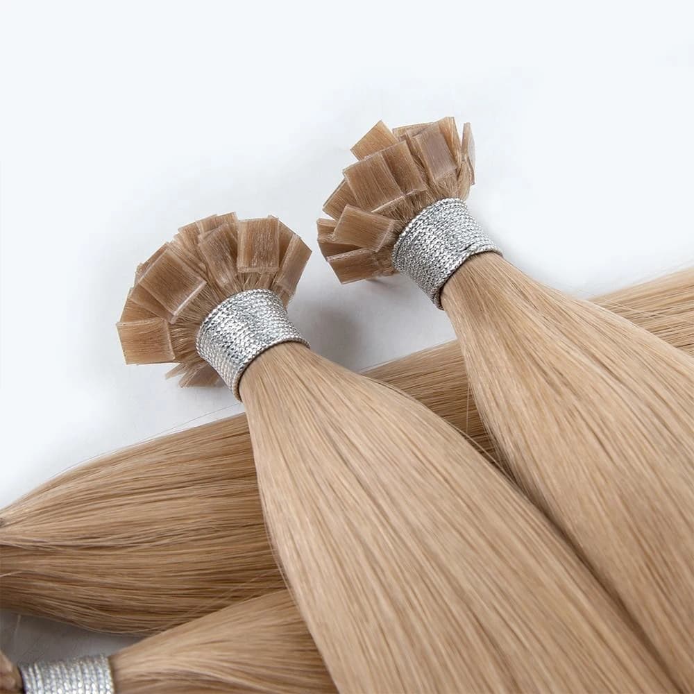 Close-up of blonde flat-tip hair extension bundles showing the bond ends and silver ties
